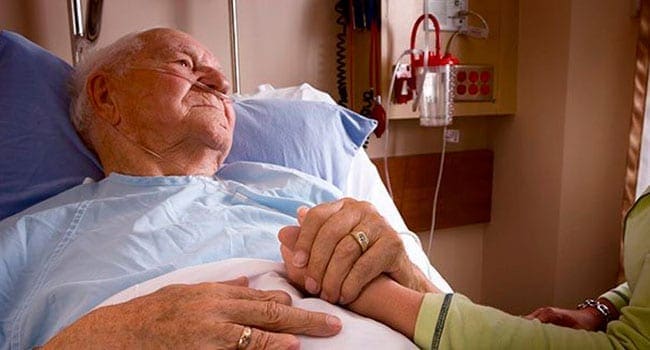 Old man lying in hospital bed holding daugher Canada’s hospital system ill-prepared for COVID-19 crisis